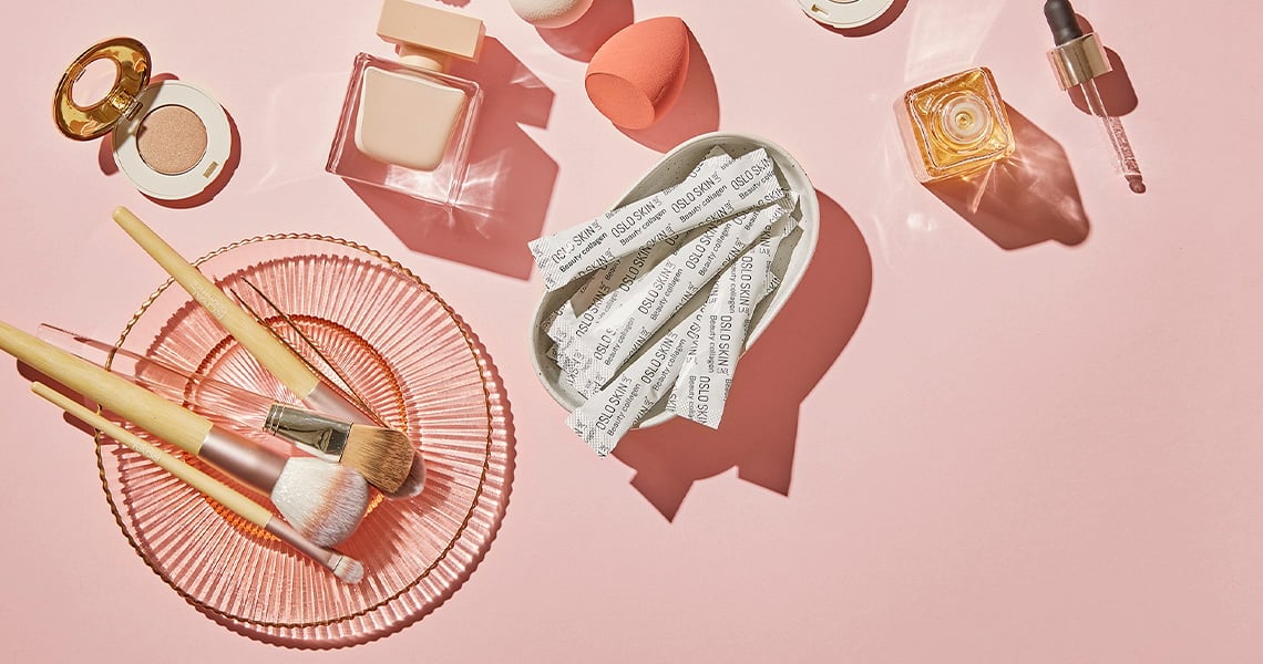 pytlíčky kolagenu The Solution na růžovém podkladu spolu s krabičkou od kolagenu a dalšími kosmetickými produkty