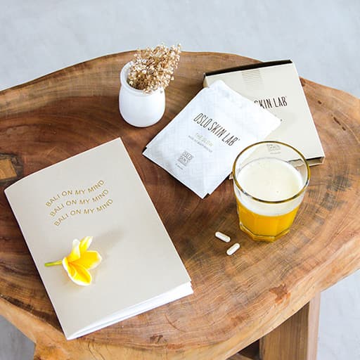 balení The Glow položené na dřevěném stolku, vedle položená sklenice s pomerančovým džusem