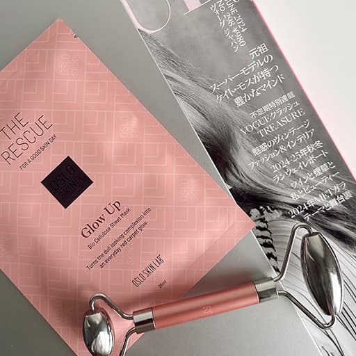 maska The Glow Up ležící na časopise Vogue v koupelně, u masky leží další kosmetické potřeby