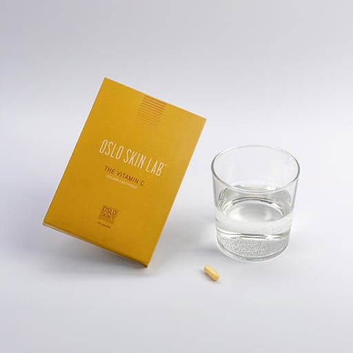 krabička vitamínu C opřená o sklenici s vodou